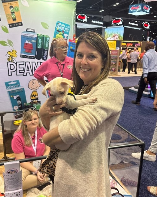 Woman holding puppy at pet trade show.