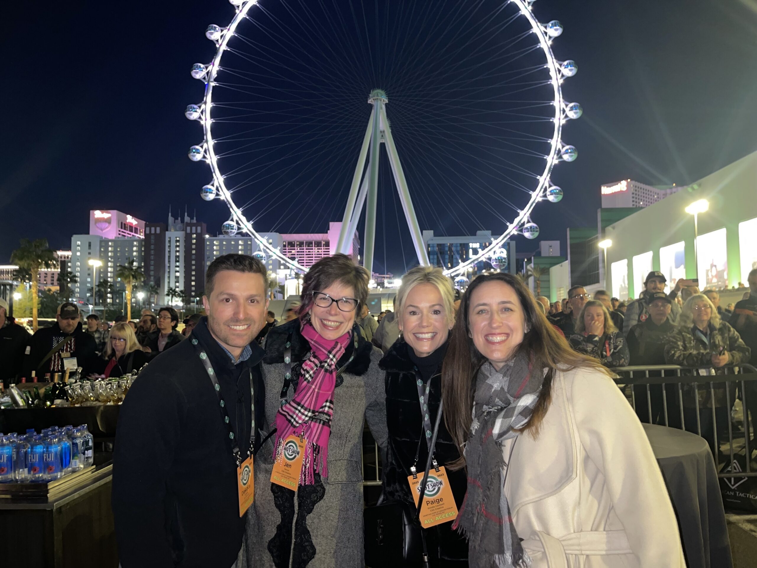 Four people standing in front of a Ferris wheel at night